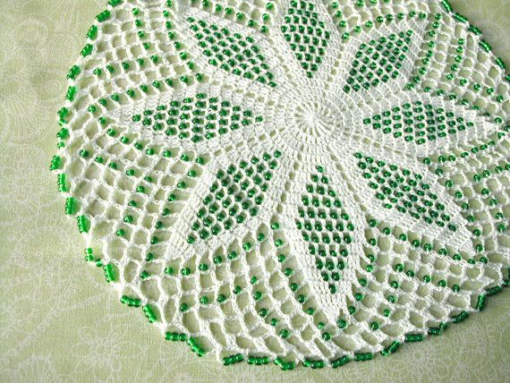 White crochet lace doily / center piece with green glass beads .
